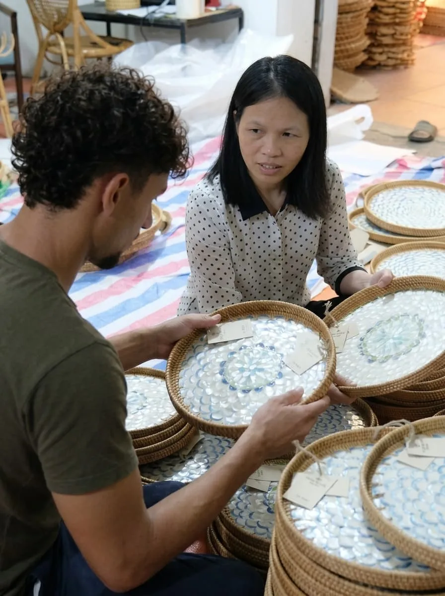 Un acheteur OSR examine des plateaux tressés avec une artisane, dans l'atelier